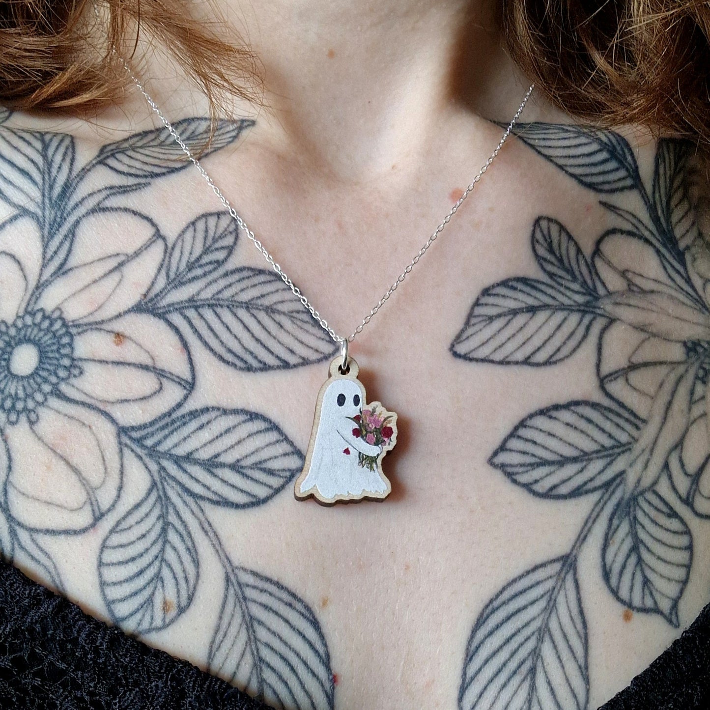 Person wearing a necklace with a ghost pendant.