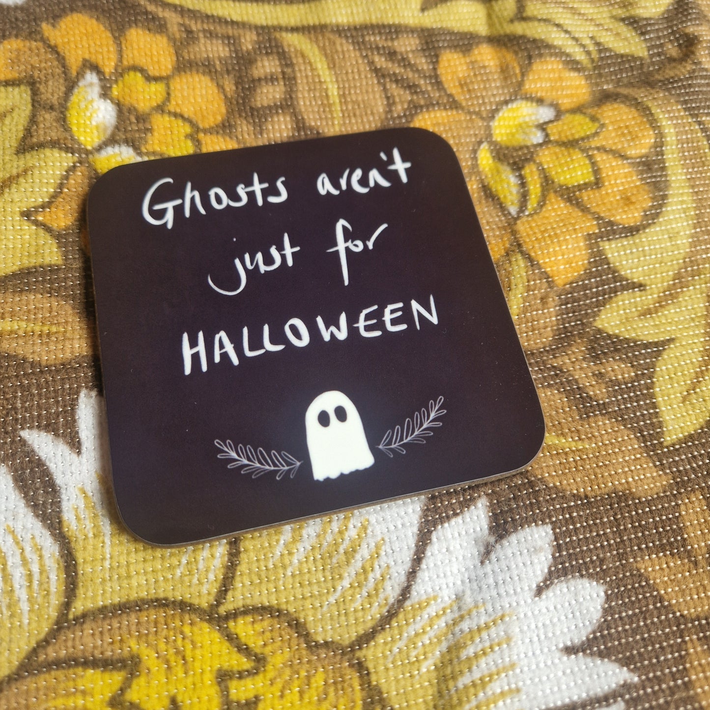 The Ghosts Aren't Just For Halloween Coaster by Duck Egg Designs features a cute ghost and leaves on floral fabric, with the phrase in white text. Printed in the UK, it's perfect for spooky charm all year round.