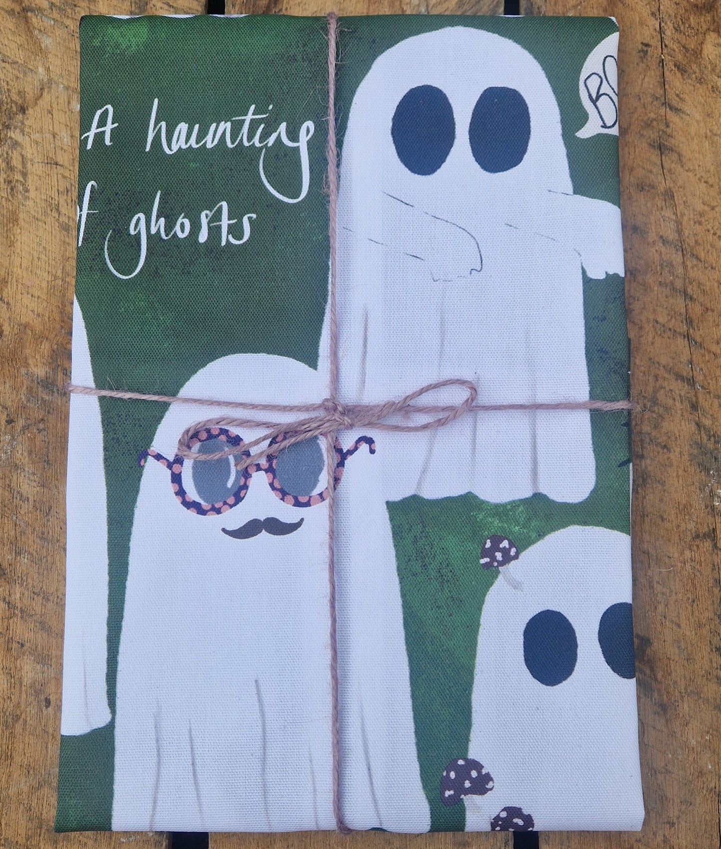 Packaged tea towel with ghost design on a wooden surface