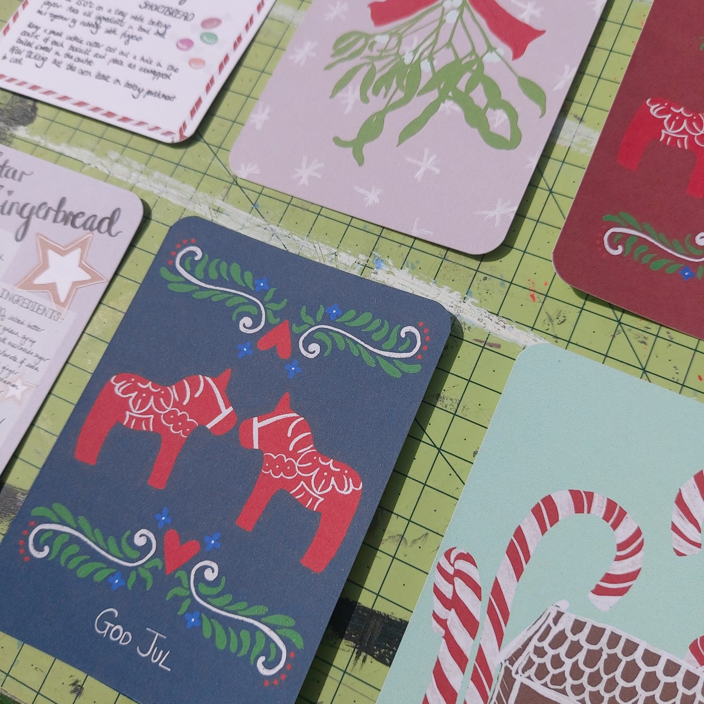 A close up of the postcards sat on a green cutting mat.
