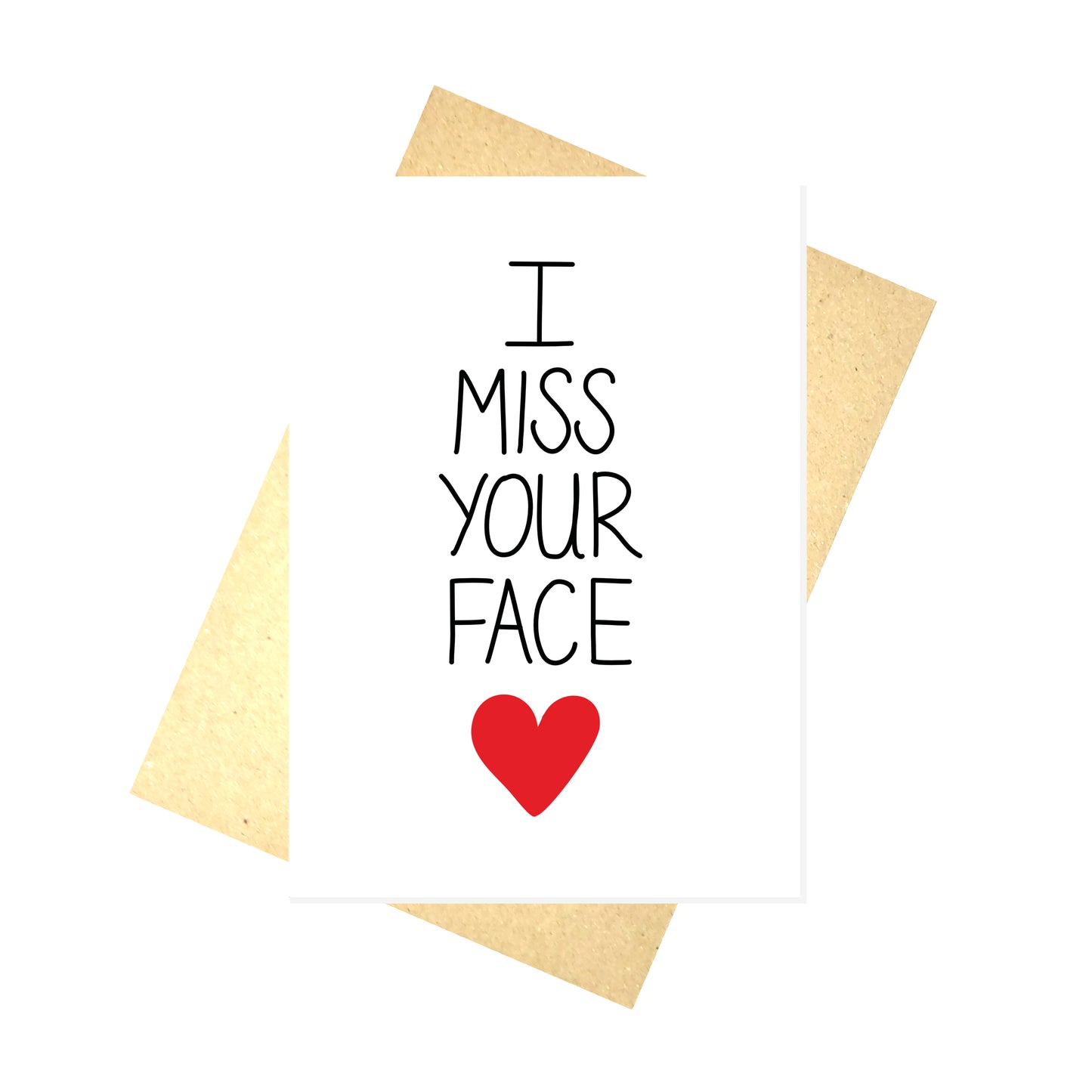 A white card with the words 'I MISS YOUR FACE' down the middle, below which is a red heart. Behind the card is a brown envelope behind which is a white background.