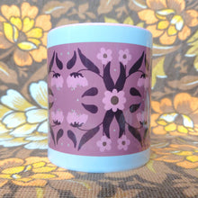 Load image into Gallery viewer, Pink and white mug with a symmetrical floral retro inspired pattern sits in front of a white and brown floral background. The mug features a pink handle and inside, with a border of white around the design.
