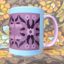 Load image into Gallery viewer, Pink and white mug with a symmetrical floral retro inspired pattern sits in front of a white and brown floral background. The mug features a pink handle and inside, with a border of white around the design.
