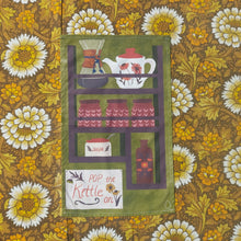 Load image into Gallery viewer, A green teatowel featuring a kitchen vintage inspired design sits on a floral brown white and yellow background.
