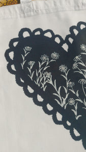 A closer view of the design on the bag showing a section of the black heart with the daisies growing through it.