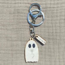 Load image into Gallery viewer, A keyring featuring a white ghost holding a grey kitten as well as a mini charm with the Duck Egg Designs logo. Behind the keyring is a grey fabric background.
