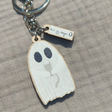 Load image into Gallery viewer, A white ghost keyring holding a grey kitten sits on a light grey fabric background. 
