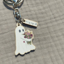 Load image into Gallery viewer, A close up of the ghost keyring - the ghost is hugging a bunch of flowers in muted green, yellow, red and dusky pink; with a couple of red petals falling from the bunch. Above the ghost you can see a white and black Duck Egg Designs logo, and the keyring sits on a light grey background.
