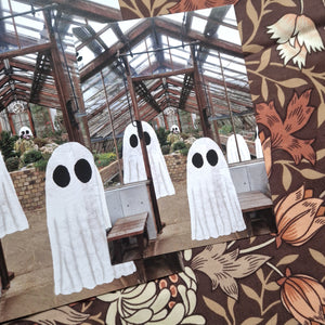 A close up of the smaller print size with the bigger print behind it on the left. The print features a greenhouse with a group of ghost haunting it.