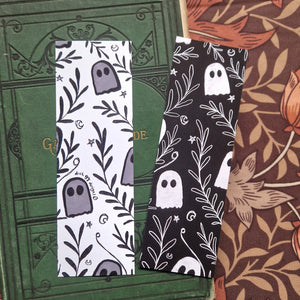 An image of the front and back of the bookmark together showing the black and white versions of the ghost and vine pattern. Behind the bookmarks you can see an old green gardening book behind which is a brown floral patterned fabric.