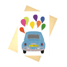 Load image into Gallery viewer, A white card with a blue VW beetle seen from the back with colourful balloons hanging from the top. The Beatles number plate reads ‘JU5T M4RRI3D’. Behind the card you can see a brown paper envelope on a white background. 
