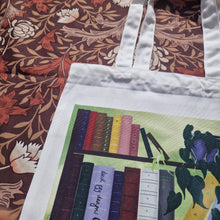 Load image into Gallery viewer, A close up view of the top left of the bag, showing the colourful books on the dark brown shelving as well as the trailing dark green philodendron. Above and to the left of the bag you can see a brown retro floral patterned background.
