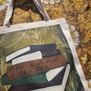 A close up view of the top of the bag showing the book stack design in greater detail. Behind the white bag you can see a warm brown retro floral patterned background.