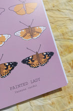 Load image into Gallery viewer, A close up view of the bottom left corner of the card showing the writing on it as well as some of the illustration. Behind the card is a naturally dyed fabric featuring warm orange tones.
