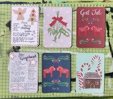 Load image into Gallery viewer, All six postcard designs shown in two rows of three on a green cutting mat.
