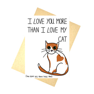 A white card featuring a ginger and white cat with a love heart marking on their side. Above the cat are the words 'I love you more than I love my cat' in black handwritten writing. Below the cat are the words '(but don't tell them I said that)'. Behind the card you can see a recycled brown envelope, behind which is a white background.