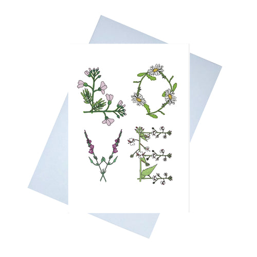 A white card with the word LOVE written on it in large. The letters are made up of flowers that begin with the same letter. L - lady's smock. O - ox-eye daisy, V - vervain and E - enchanters nightshade. Behind the card is a lilac envelope, behind which is a white background.