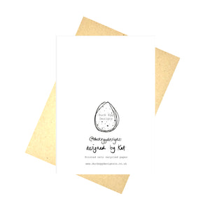 Back of the card showing the Duck Egg Designs logo as well as our instagram handle, the words 'designed by Kat' in black handwriting, and our website address. Behind the card you can see a brown envelope in front of a white background.