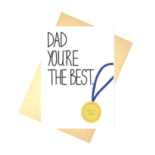 Load image into Gallery viewer, A white card on top of a brown envelope and a white background. The card features the words DAD YOU&#39;RE THE BEST along the left hand side in black handwriting. On the right angled towards the middle of the card is a golden medal that reads NO. 1 DAD with a blue ribbon falling off the side of the card.
