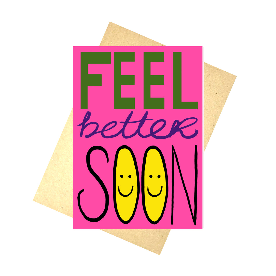 Bright pink card featuring the words 'FEEL better SOON' with feel in block green letters, better in purple cursive writing and soon in black capital letters with yellow smiley faces on the inside of the os. Behind the card is a recycled brown envelope behind which is a white background.