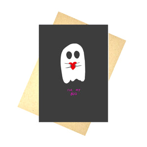 A black card with a white ghost on it holding a red heart above the words 'FOR MY BOO' on hot pink writing. Behind the card you can see a brown envelope in front of a white background.
