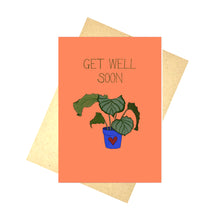 Load image into Gallery viewer, Orange card featuring a potted calathea in a blue pot with a red heart under the words &#39;GET WELL SOON&#39; in dark green writing. Behind the card you can see a recycled brown envelope behind which is a white background.
