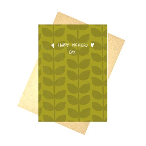 A warm green card featuring a darker green leafy vine pattern with the words 'Happy Mothers Day' in white with a little heart on either side. Behind the card is a white background and a brown envelope.