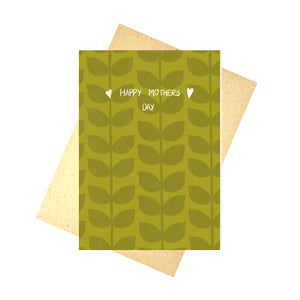 A warm green card featuring a darker green leafy vine pattern with the words 'Happy Mothers Day' in white with a little heart on either side. Behind the card is a white background and a brown envelope.