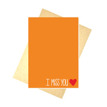 Load image into Gallery viewer, Warm orange card featuring the words &#39;I MISS YOU&#39; in white in the bottom left next to a small red heart. Behind the card a brown envelope on a white background is visible.
