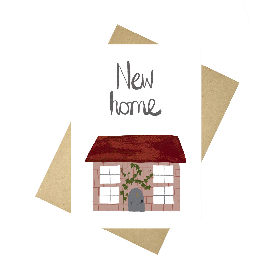 A white card featuring a small pink house with a trailing vine growing up the side, a grey door and a textured red roof. Above the house the words 'New home' are visible in grey in stylised handwriting.  Behind the card is a brown envelope, behind which is a white background.