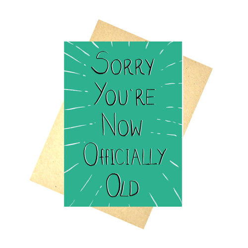 Green card with the words 'Sorry You're Now Officially Old' in black with with highlights behind, with white lines coming out from the words to the edge of the card. Behind the card you can see a brown envelope, behind which is a white background.