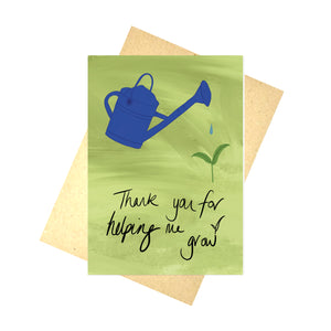 A green multi tonal card sits on top of a recycled brown envelope in front of a white background. The card features a royal blue watering can, with a drop of water dripping towards a small green plant. Handwritten words in black underneath say 'Thank you for helping me grow' with leaves growing out of the w.